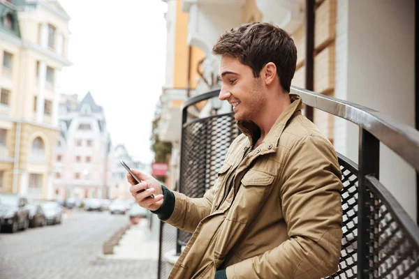 Jonge gelukkig man lopen op straat en chatten via de telefoon — Stockfoto