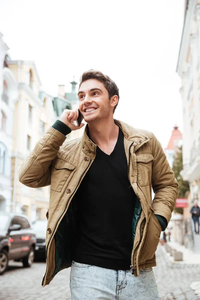 Cheerful man walking on the street while talking by phone. — Stock Photo, Image