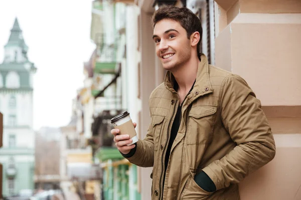 Cheerful young man walking while holding cup of coffee. — Stock Photo, Image