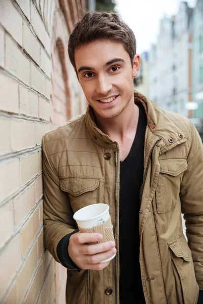 Cheerful young man walking on the street and holding coffee. — Stock Photo, Image