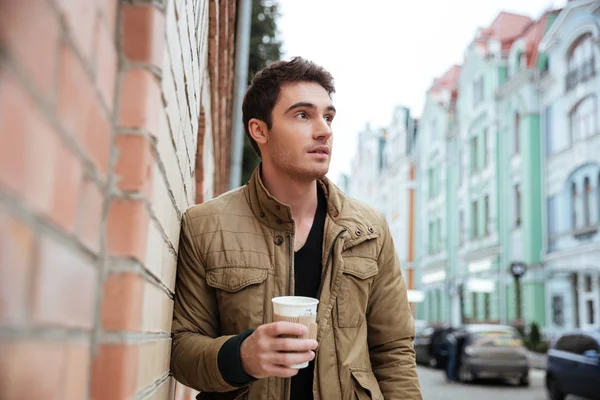 Attraktiv allvarlig ung man promenader medan du håller kaffe. — Stockfoto