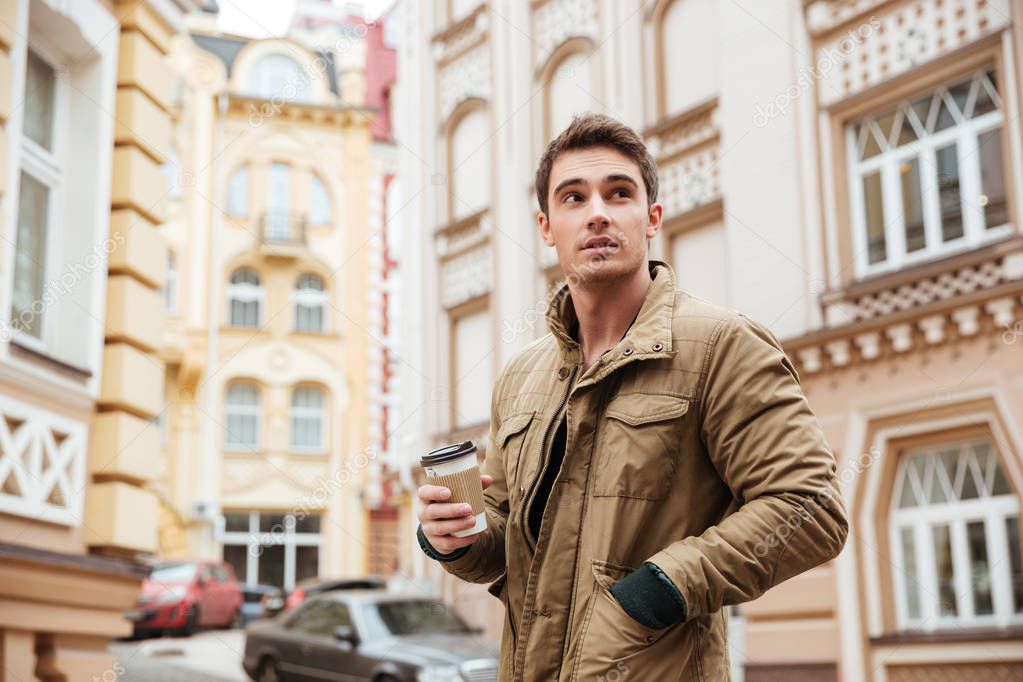 Handsome man walking on the street while holding coffee.