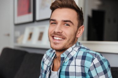 Evde kanepede oturan neşeli genç adam