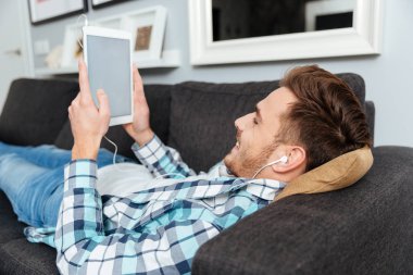 Tablet bilgisayar müzik dinleme sırasında kullanan mutlu kıl adam