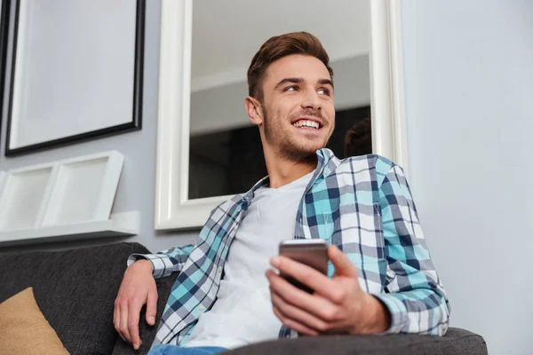 Hombre feliz en casa mirando a un lado mientras charlas por teléfono — Foto de Stock
