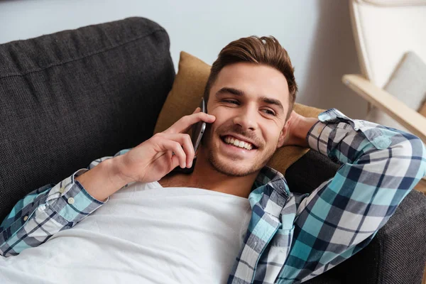 Risate setole uomo si trova sul divano mentre parla per telefono — Foto Stock