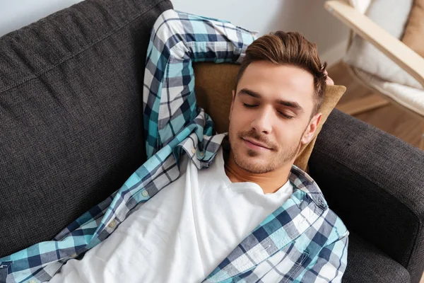 Stanco giovane uomo si trova sul divano a casa e dormire — Foto Stock