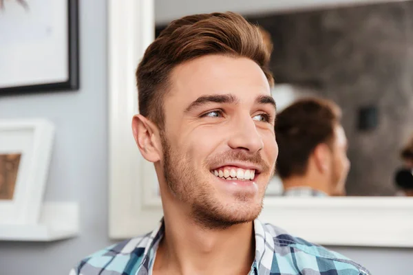 Fröhlicher junger Mann sitzt zu Hause auf Sofa — Stockfoto