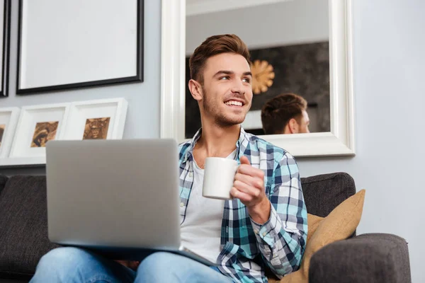 Glad borst man använder bärbar dator medan du dricker te. — Stockfoto