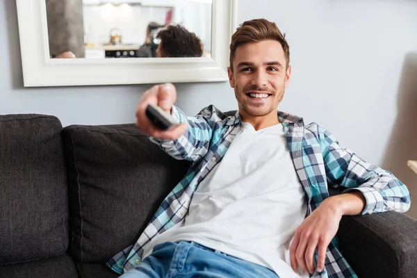 Uomo setola sorridente che tiene il telecomando mentre guarda la TV . — Foto Stock