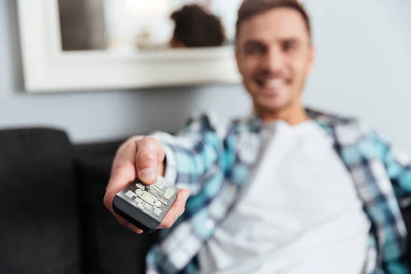Happy young bristle holding remote control while watching TV — Stock Photo, Image