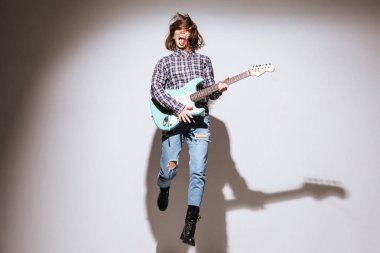 Gitar beyaz arka plan üzerinde tutarak ve atlama çekici kadın