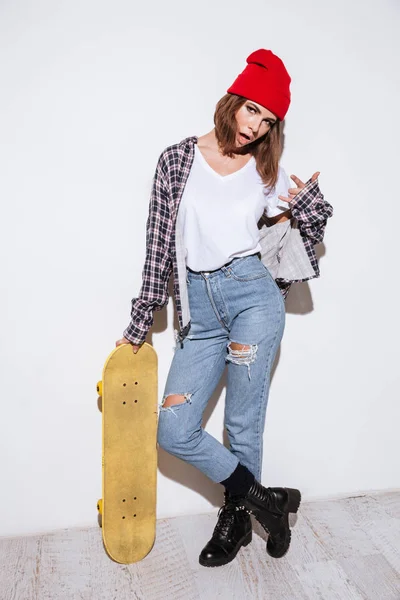 Κυρία κάνει ροκ χειρονομία και κρατώντας skateboard — Φωτογραφία Αρχείου