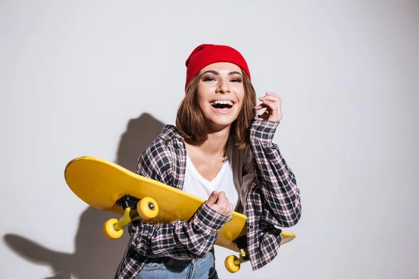 Femme heureuse isolé sur fond blanc tenant skateboard — Photo