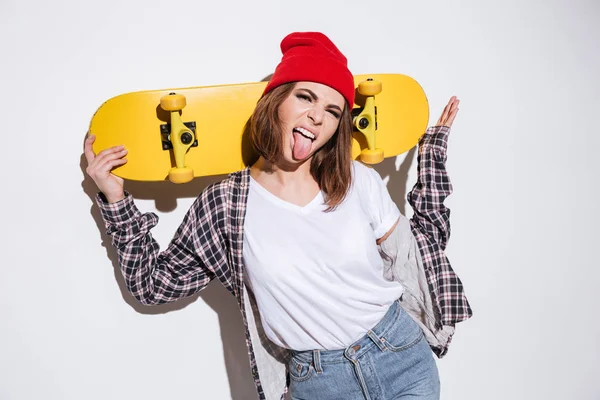 Kvinna visar tungan och hålla skateboard — Stockfoto