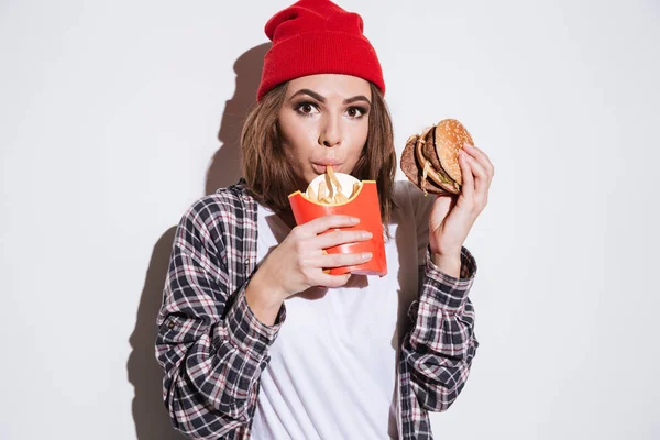 Mulher com fome segurando batatas fritas e hambúrguer — Fotografia de Stock
