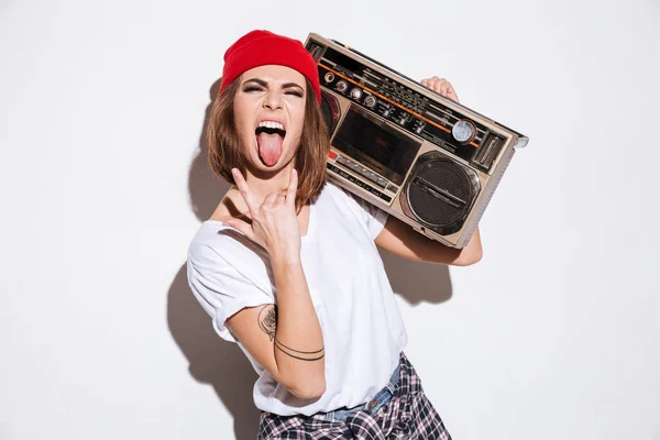 Woman holding tape recorder and make rock gesture showing tongue.