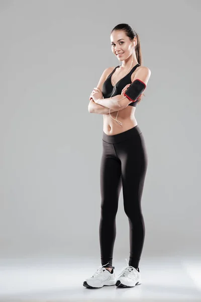 Volle Länge der lächelnden selbstbewussten Sportlerin, die mit verschränkten Armen steht — Stockfoto