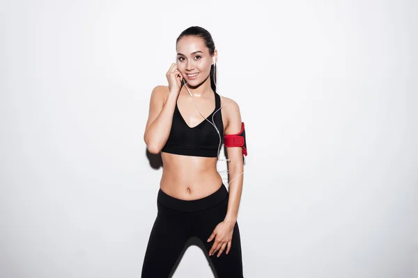 Glückliche Fitness-Frau mit Armbinde im Stehen und Musikhören — Stockfoto