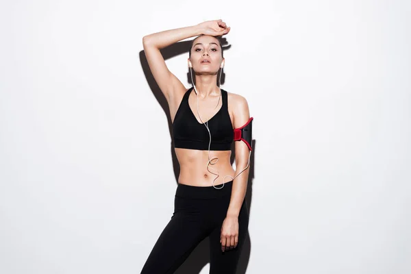 Attractive young woman athlete with armband and earphones standing — Stock Photo, Image