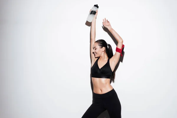 Fröhlich entspannte junge Sportlerin steht und hält eine Flasche Wasser — Stockfoto