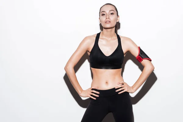 Selbstbewusste junge Fitness-Frau mit Armbinde in schwarzer Sportbekleidung — Stockfoto