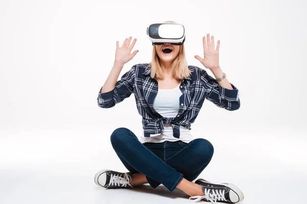 Happy amazed young woman sitting on floor wearing VR glasses — Stock Photo, Image