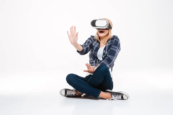 Amazed woman sitting on floor wearing VR glasses — Stock Photo, Image