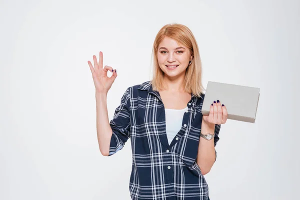 Positive young woman holding book and make okay gesture. — Stock Photo, Image