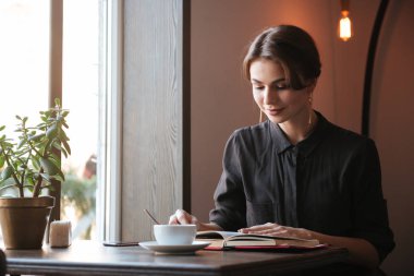 Kitap okuma masada oturan güzel genç bayan