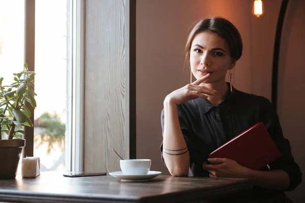 Jolie jeune femme tenant livre dans un café — Photo