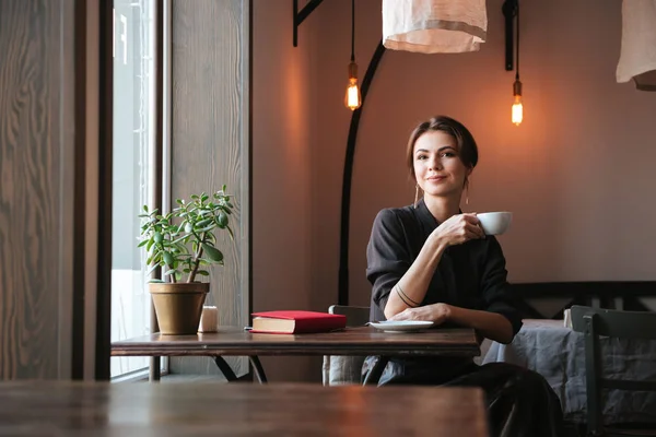 Mujer joven y bonita sentada a la mesa en la cafetería —  Fotos de Stock