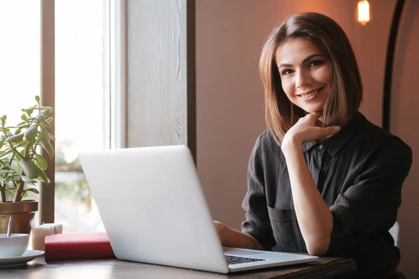 Pretty young woman using laptop computer. Look at camera. — Stock Photo, Image