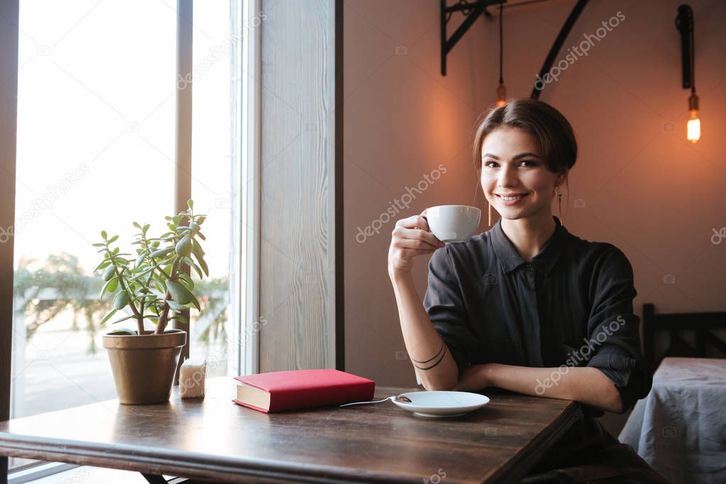 Amazing cheerful young woman drinking coffee.