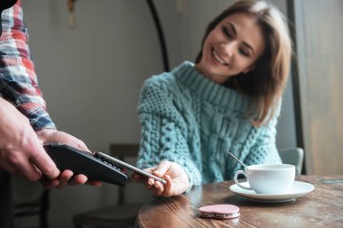 Onun emri ile telefon için genç bayan gülümseyerek öder.
