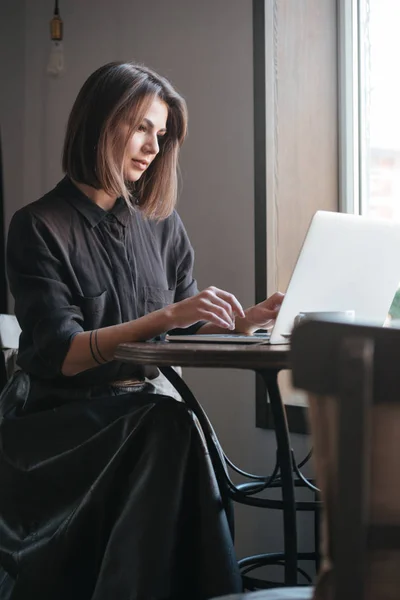 Mulher feliz sentada à mesa no café e usando laptop — Fotografia de Stock