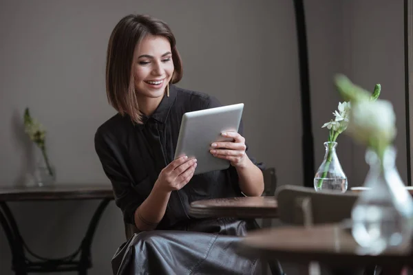 Beautiful woman sitting near window using tablet computer. — Stock Photo, Image