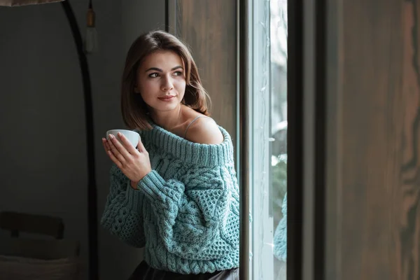 Молодая симпатичная женщина смотрит в окно в кафе — стоковое фото