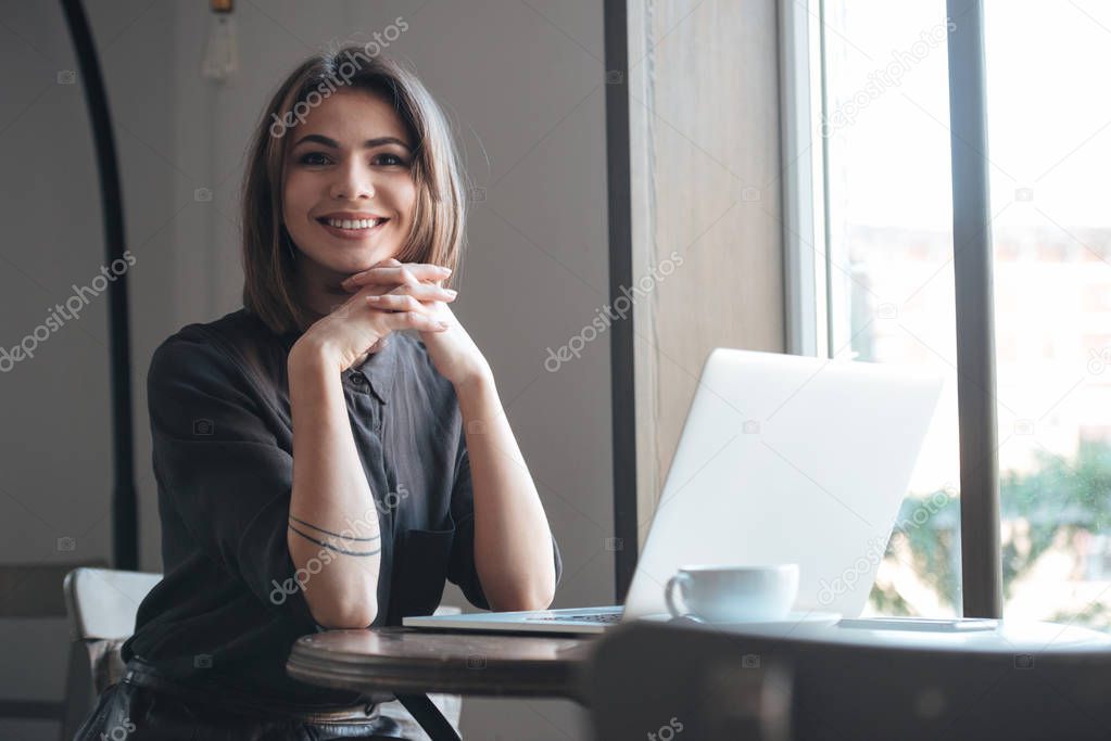 Incredible lady sitting at the table in cafe using laptop