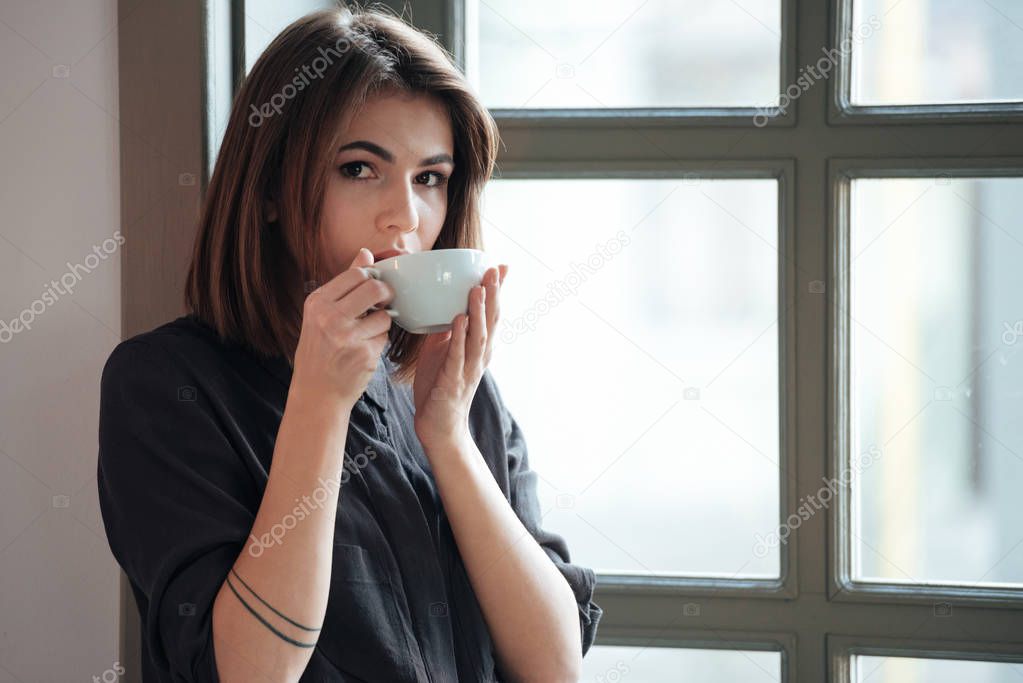Young incredible cheerful woman drinking coffee.