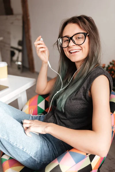Gladlynt kvinna lyssnar på musik från mobiltelefon hemma — Stockfoto