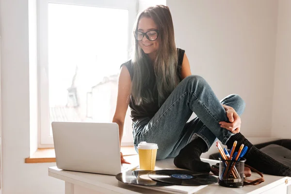 Woman sitting on the table and using laptop — Stock Photo, Image