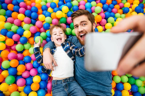 Zoon en vader selfie liggend op kleurrijke ballen houdend — Stockfoto