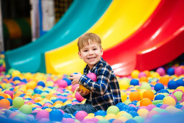 Glad liten pojke som spelar på inomhus lekplats med färgglada b — Stockfoto