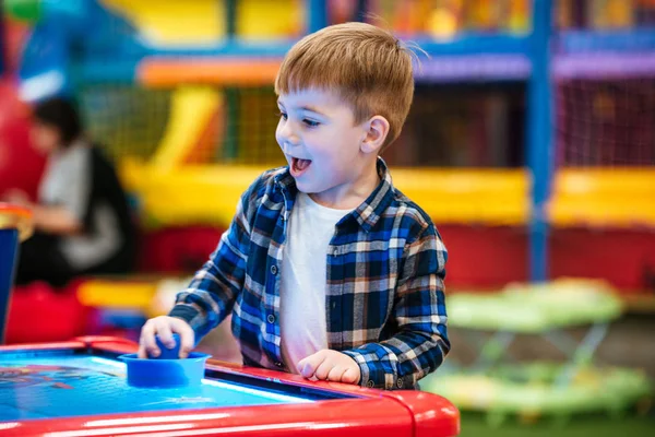 Allegro bambino che gioca a air hockey gioco al parco giochi al coperto — Foto Stock