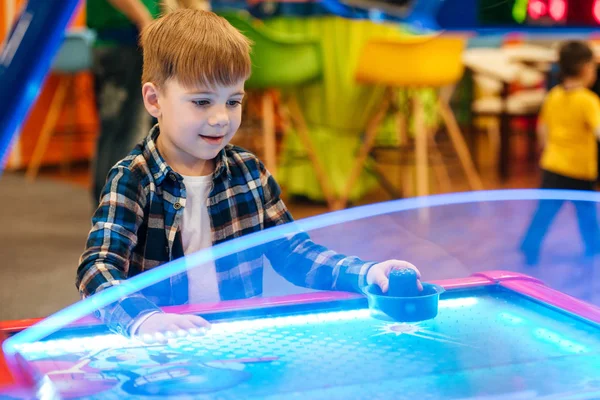 Söpö pieni poika pelaa ilmakiekkoa sisätiloissa huvipuisto — kuvapankkivalokuva