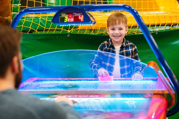 Sorridente carino bambino giocare air hockey con suo padre — Foto Stock