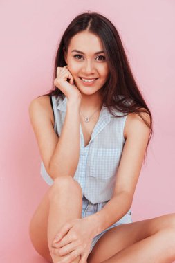 Katta oturan ve kameraya bakarak gülümseyen kadın