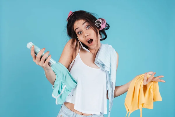 Mujer joven confundida hablando por teléfono y sosteniendo la ropa — Foto de Stock