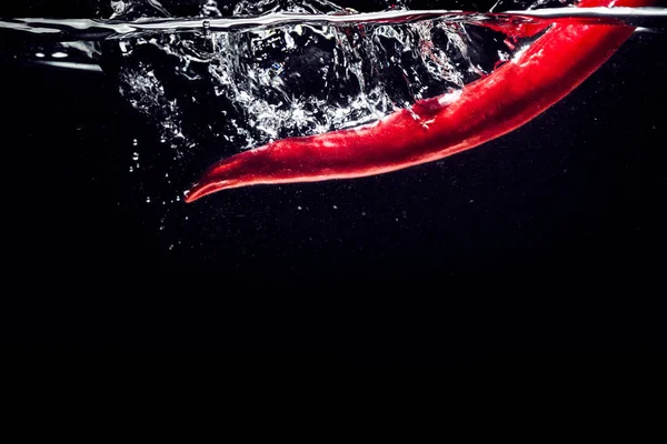 Красный перец чили падает в воду изолированы — стоковое фото